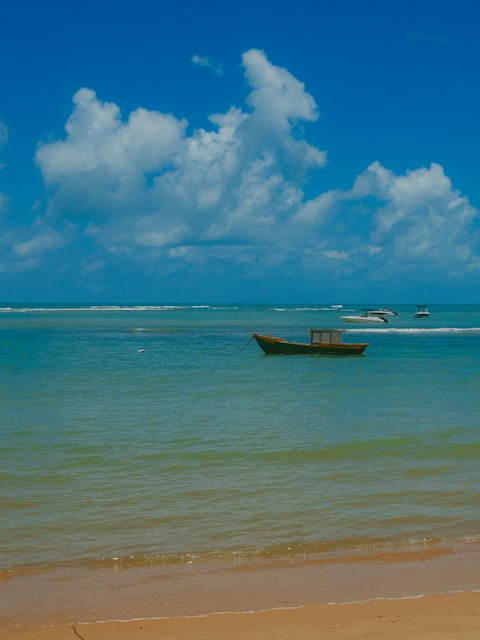 Praia de mar azul com um barco ancorado